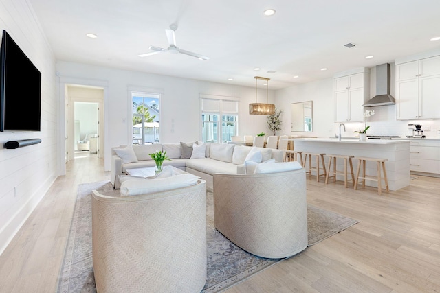 living room featuring light hardwood / wood-style flooring, ceiling fan, and sink