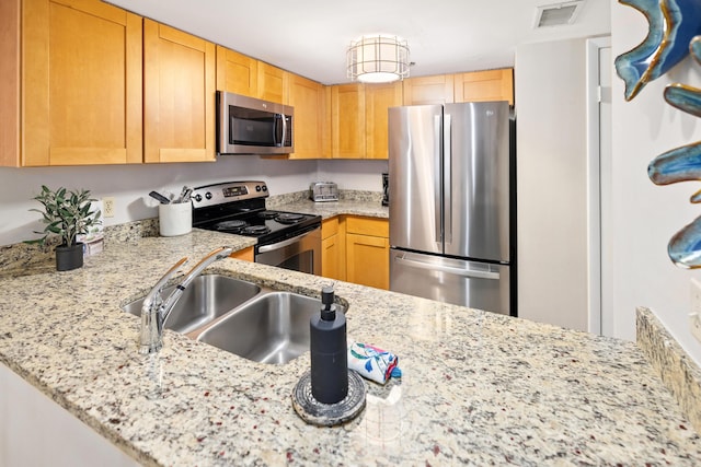 kitchen with light stone counters, a sink, visible vents, light brown cabinets, and stainless steel appliances
