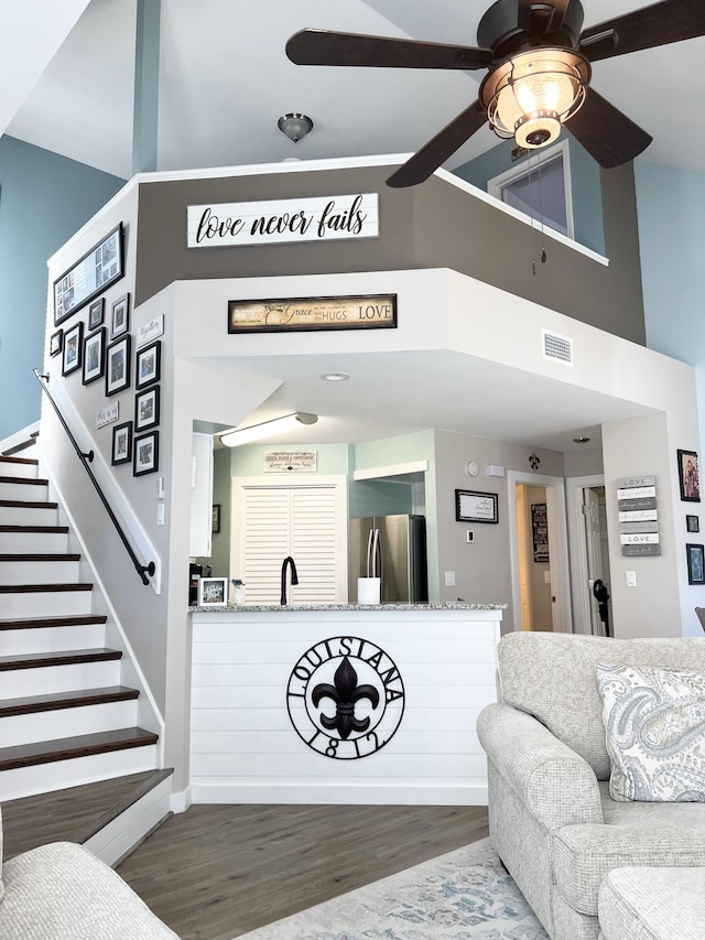 living room with ceiling fan, hardwood / wood-style flooring, sink, and a high ceiling