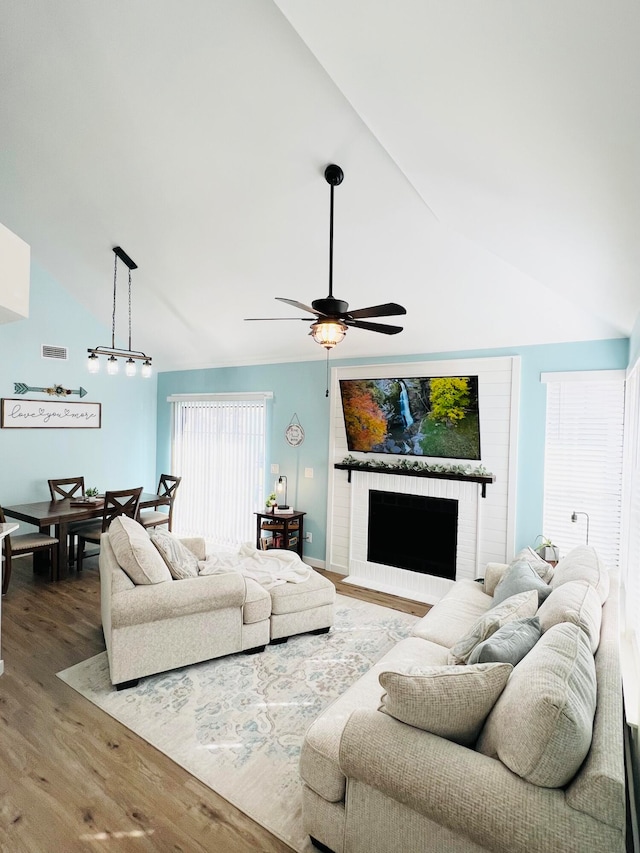 living room with high vaulted ceiling, ceiling fan, hardwood / wood-style flooring, and a fireplace