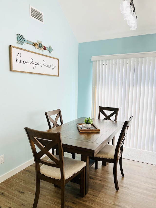 dining room featuring wood-type flooring and vaulted ceiling