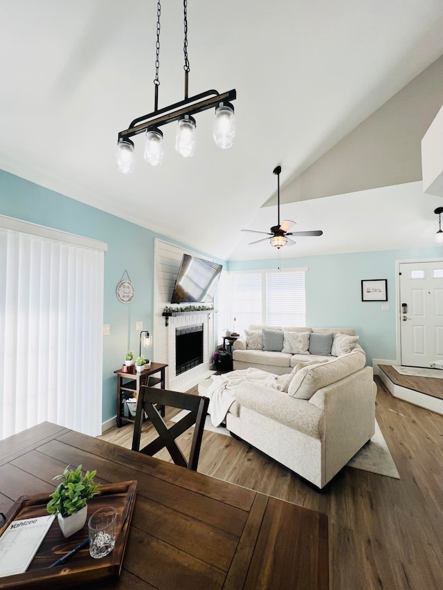 living room with a brick fireplace, lofted ceiling, ceiling fan, and dark hardwood / wood-style floors