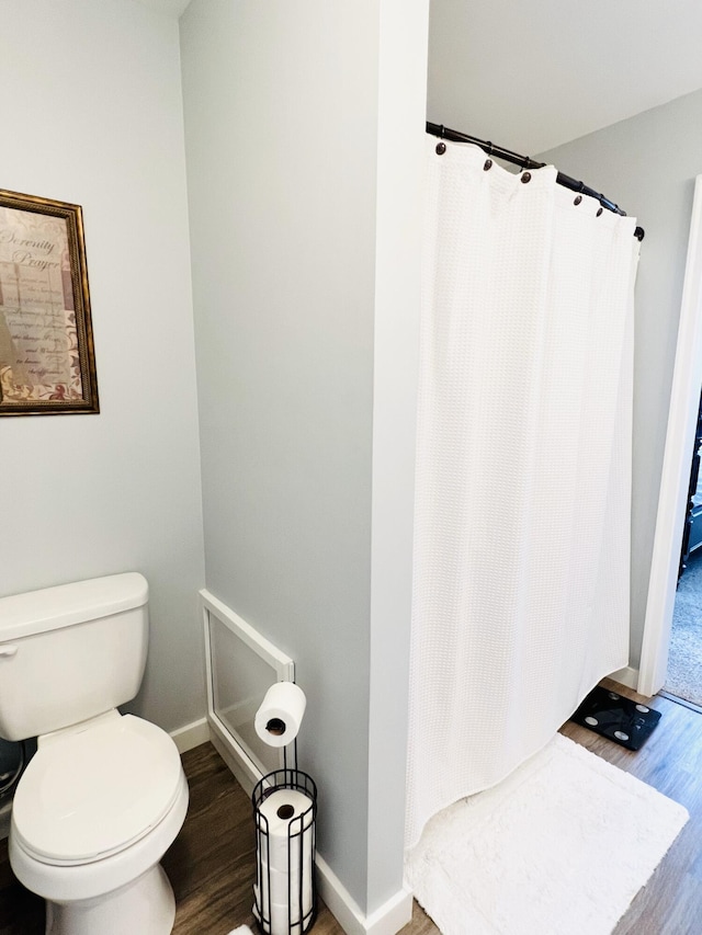 bathroom with a shower with curtain, hardwood / wood-style floors, and toilet