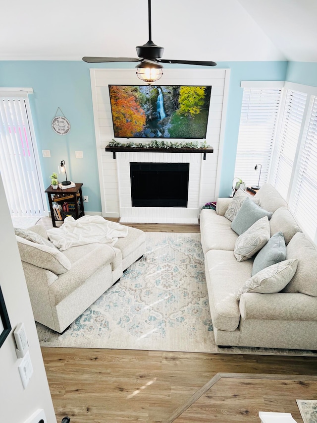 living room with a brick fireplace, hardwood / wood-style floors, and ceiling fan