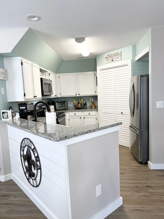 kitchen featuring dark wood-type flooring, white cabinets, kitchen peninsula, stainless steel appliances, and light stone countertops