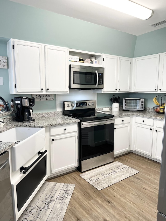 kitchen featuring white cabinets, stainless steel appliances, and light hardwood / wood-style floors