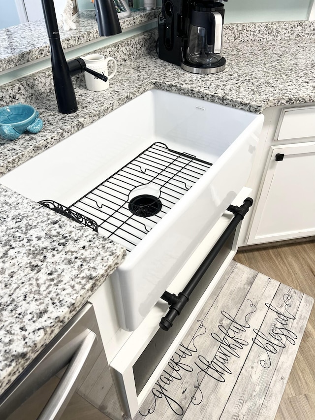 details featuring light stone countertops, light hardwood / wood-style flooring, and white cabinetry