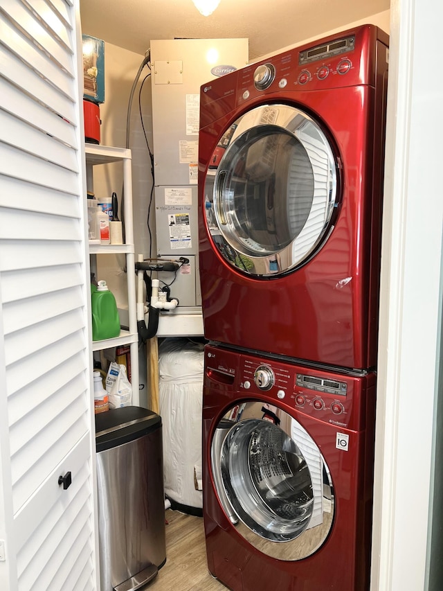 clothes washing area with stacked washer / drying machine and light wood-type flooring