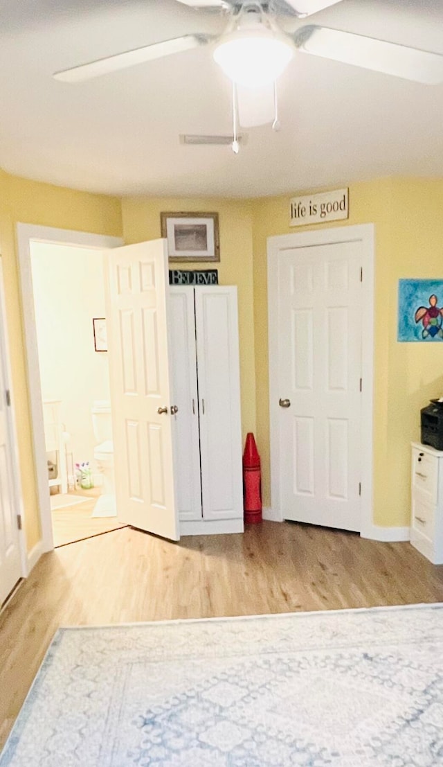 unfurnished bedroom with ensuite bath, ceiling fan, and hardwood / wood-style flooring