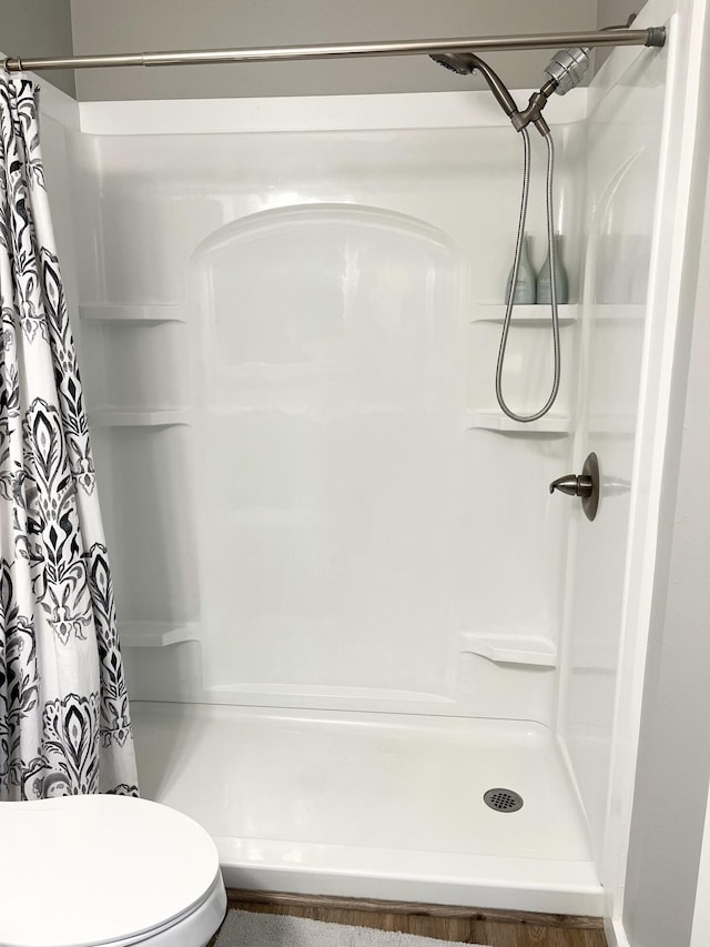 bathroom with toilet and a shower with shower curtain