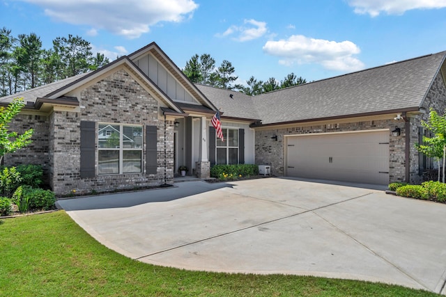 craftsman house with an attached garage, a shingled roof, concrete driveway, board and batten siding, and brick siding