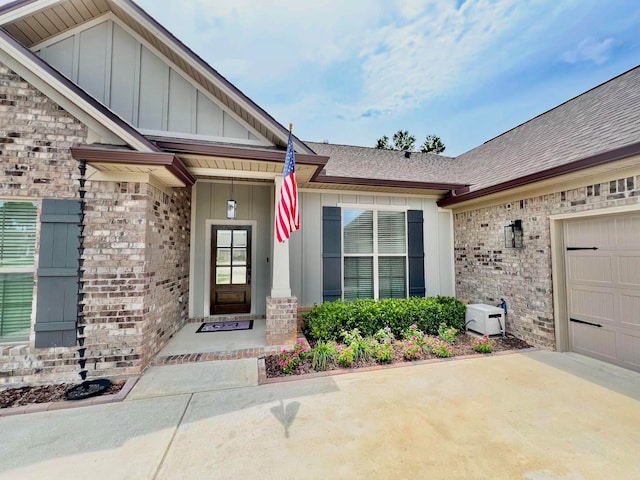 doorway to property with a garage, brick siding, and board and batten siding