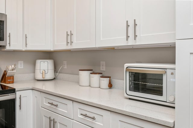 kitchen featuring white cabinetry, light stone countertops, and stainless steel appliances