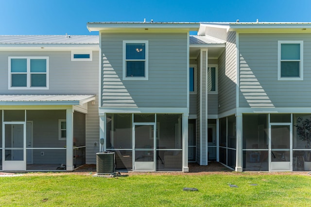 rear view of house featuring a sunroom, central AC unit, and a yard