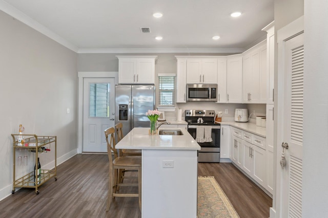 kitchen with dark wood-type flooring, a kitchen island with sink, sink, white cabinets, and stainless steel appliances