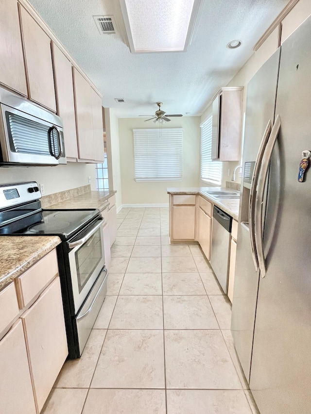 kitchen with ceiling fan, light tile patterned floors, stainless steel appliances, and sink