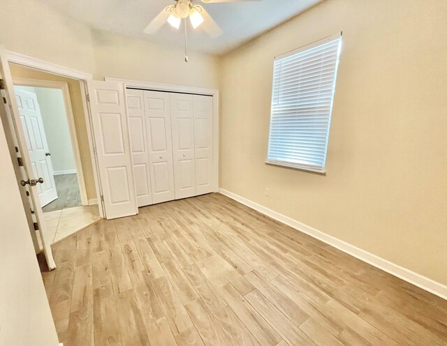 unfurnished bedroom with ceiling fan, a closet, and light hardwood / wood-style floors