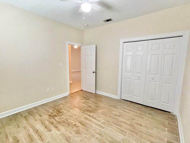 unfurnished bedroom featuring ceiling fan, light hardwood / wood-style flooring, and a closet