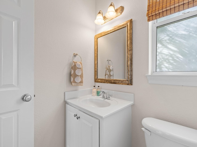 bathroom with vanity, toilet, and a healthy amount of sunlight