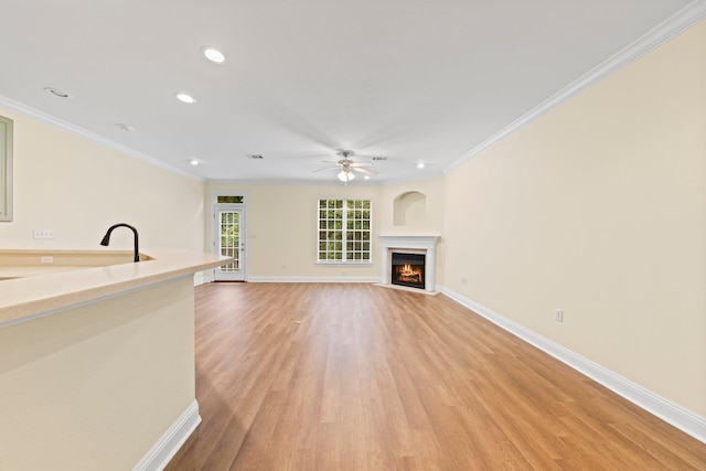 unfurnished living room with light wood-type flooring, crown molding, and ceiling fan