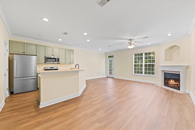 kitchen featuring ceiling fan, ornamental molding, stainless steel appliances, green cabinets, and light wood-type flooring