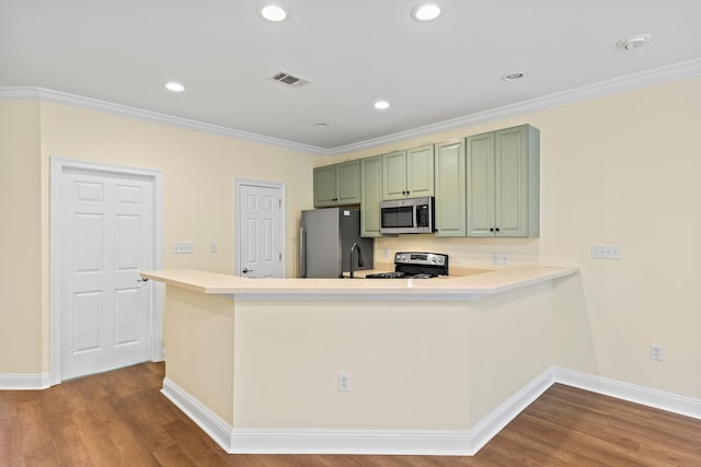 kitchen with ornamental molding, kitchen peninsula, appliances with stainless steel finishes, green cabinets, and hardwood / wood-style floors