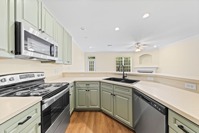 kitchen featuring light wood-type flooring, sink, appliances with stainless steel finishes, ornamental molding, and ceiling fan