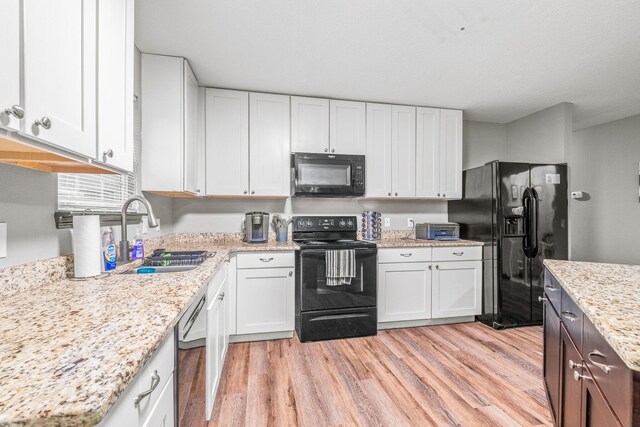 kitchen with light wood-type flooring, sink, white cabinetry, black appliances, and light stone countertops