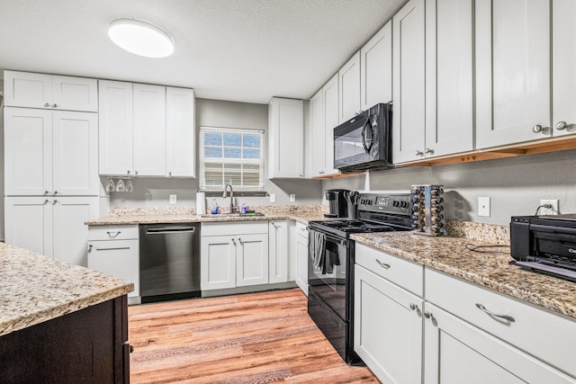 kitchen featuring white cabinets, sink, a textured ceiling, black appliances, and light hardwood / wood-style floors