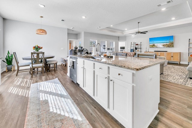 kitchen with sink, white cabinetry, stainless steel dishwasher, pendant lighting, and a kitchen island with sink