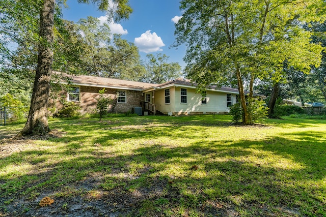 rear view of property featuring a lawn and central air condition unit