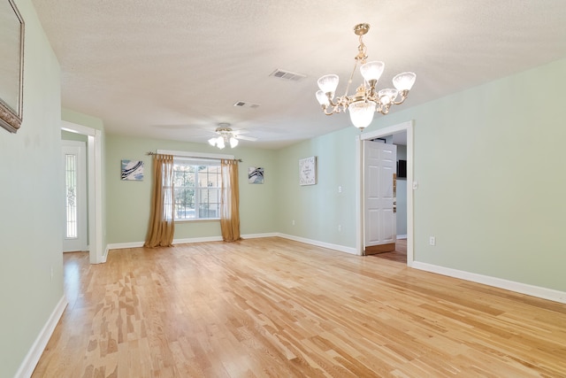 spare room featuring ceiling fan with notable chandelier, light hardwood / wood-style floors, and a textured ceiling