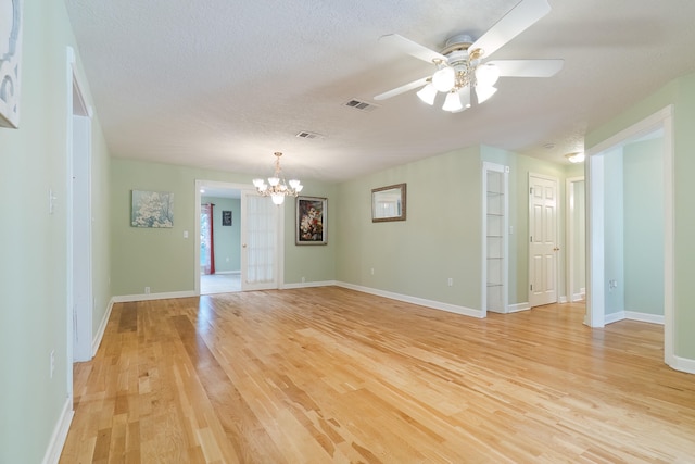 empty room featuring ceiling fan with notable chandelier, light hardwood / wood-style floors, and a textured ceiling