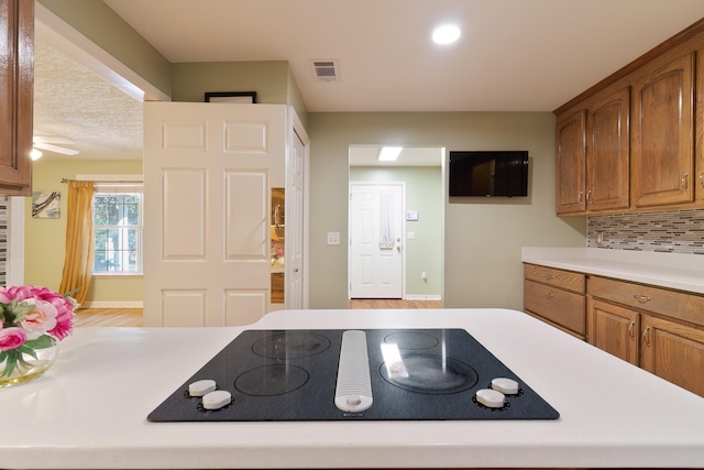 kitchen featuring black electric cooktop, backsplash, and ceiling fan