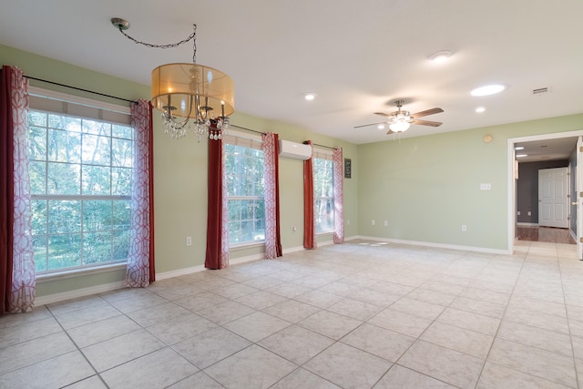 tiled empty room with a wall mounted AC, ceiling fan with notable chandelier, and a wealth of natural light