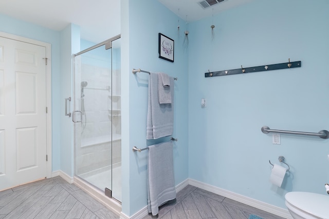 bathroom with hardwood / wood-style floors, a shower with door, and toilet