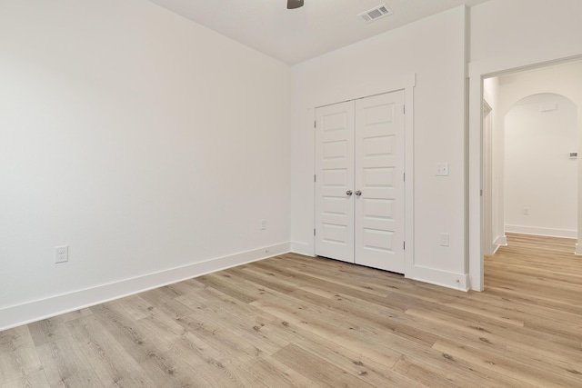 unfurnished bedroom with ceiling fan, light wood-type flooring, and a closet