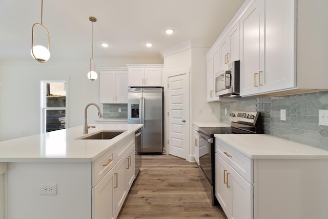 kitchen featuring pendant lighting, sink, white cabinetry, stainless steel appliances, and an island with sink