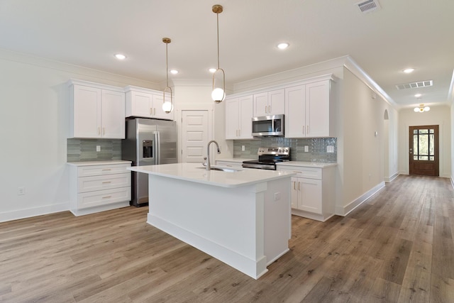 kitchen with white cabinetry, appliances with stainless steel finishes, sink, and a center island with sink