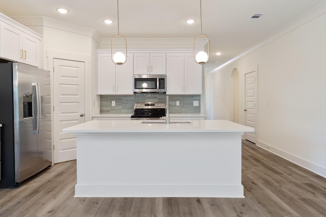 kitchen featuring pendant lighting, stainless steel appliances, a center island with sink, and white cabinets