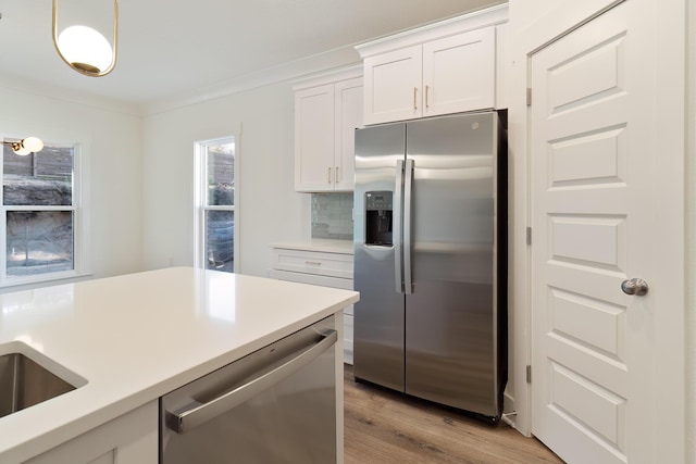 kitchen featuring appliances with stainless steel finishes, decorative light fixtures, white cabinets, decorative backsplash, and light wood-type flooring