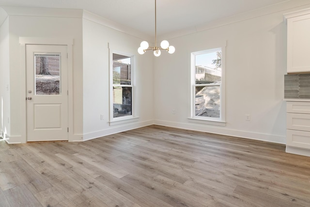 unfurnished dining area featuring crown molding, a notable chandelier, and light hardwood / wood-style flooring