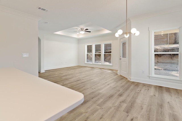 interior space with crown molding, ceiling fan with notable chandelier, light wood-type flooring, and a tray ceiling