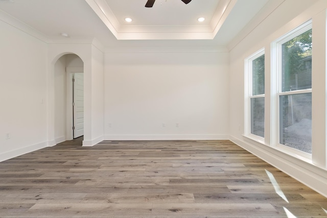 empty room featuring hardwood / wood-style flooring, ceiling fan, and a tray ceiling