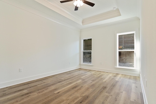 empty room featuring ceiling fan, ornamental molding, a tray ceiling, and light hardwood / wood-style flooring