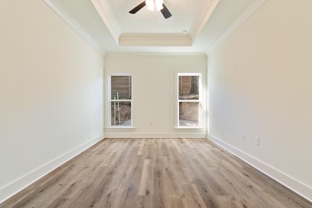 empty room featuring ceiling fan, ornamental molding, a raised ceiling, and light hardwood / wood-style flooring