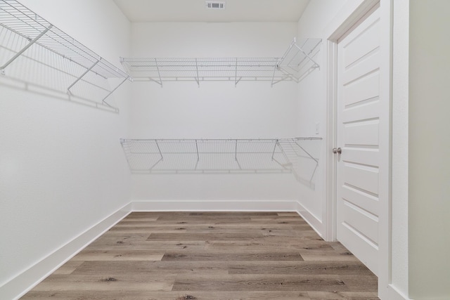 walk in closet with hardwood / wood-style flooring