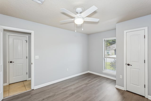 empty room with a textured ceiling, hardwood / wood-style flooring, and ceiling fan