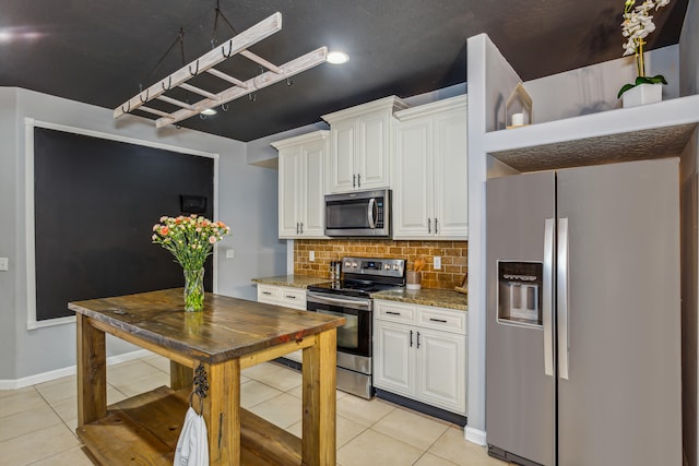 kitchen featuring decorative backsplash, light tile patterned floors, appliances with stainless steel finishes, white cabinetry, and light stone countertops