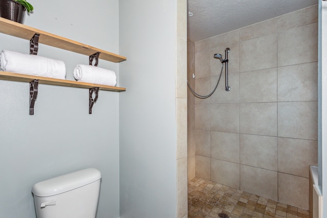 bathroom featuring tiled shower, a textured ceiling, and toilet